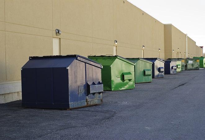 a construction worker unloading debris into a blue dumpster in Brunswick, ME